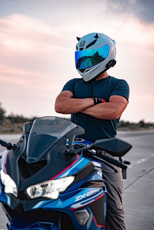 Free A confident motorcyclist poses with their sleek sports bike on a deserted road at sunset, showcasing adrenaline and adventure. Stock Photo
