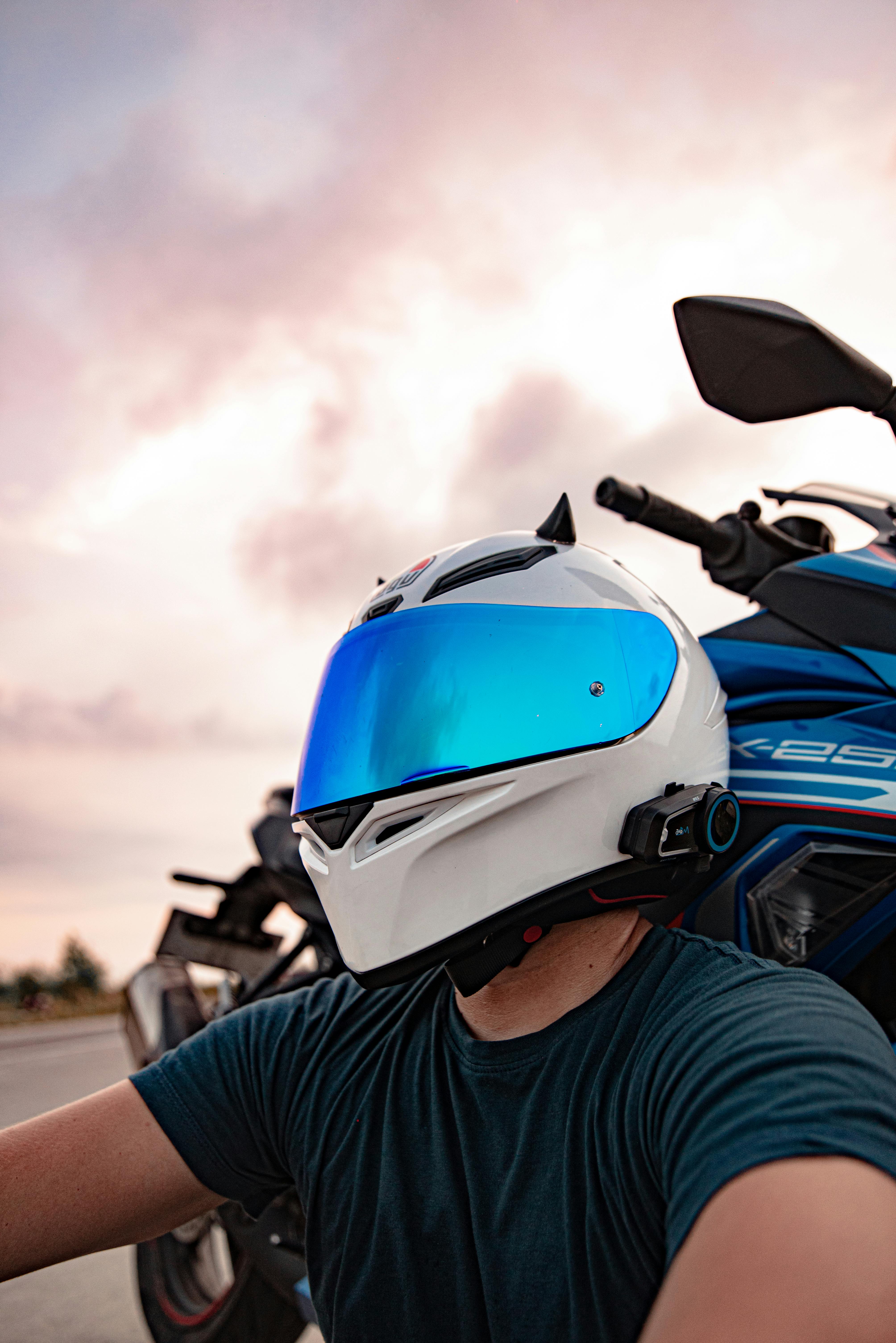 Biker in blue visor helmet on a motorcycle during sunset in Bali, Indonesia.