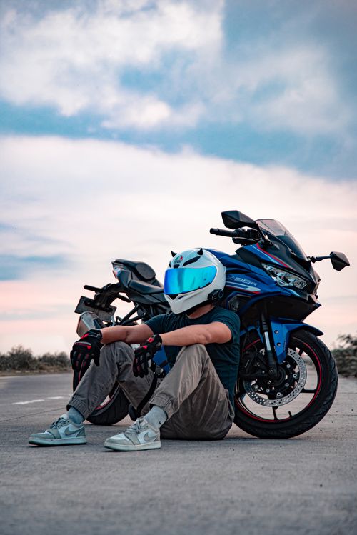 Free A motorcyclist resting on a road in Bali, Indonesia, showcasing a modern motorcycle and helmet under a bright sky. Stock Photo