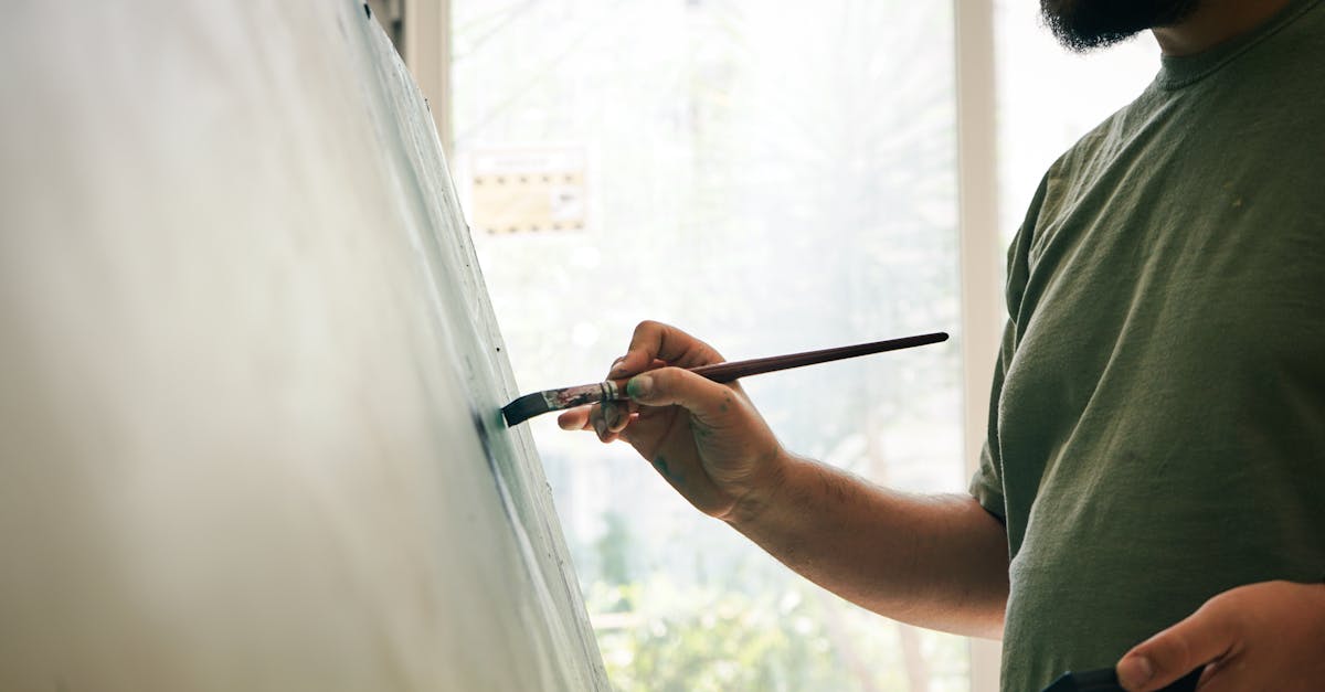 Male artist painting on a canvas in a bright studio, focusing on his creative work.