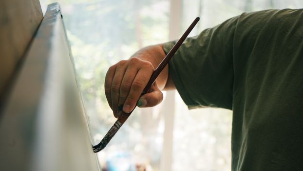 Close-up of an artist painting on a canvas indoors. Creative and calm atmosphere in the studio.