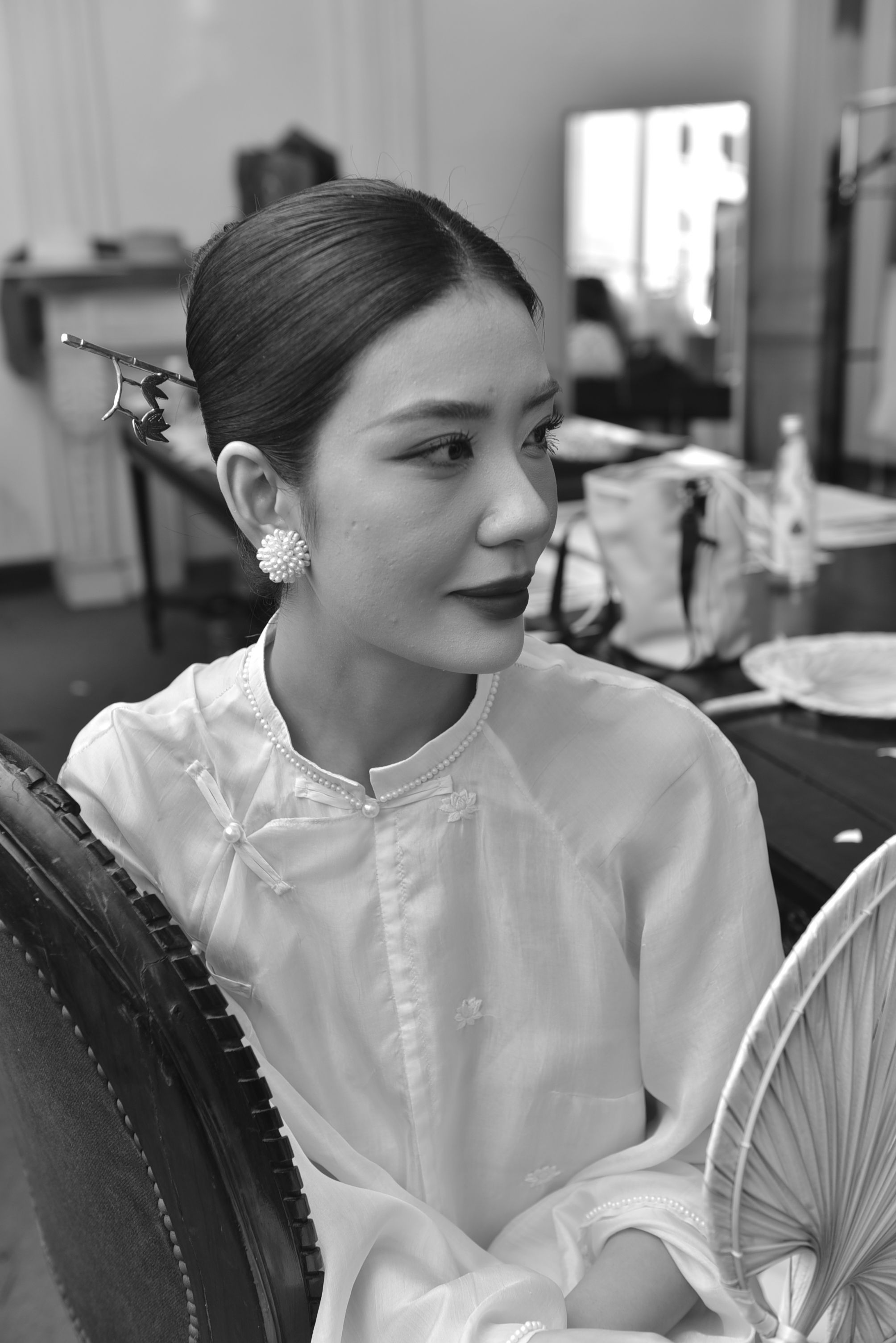 Black and white portrait of a woman in traditional clothing with hair accessory and circular fan.
