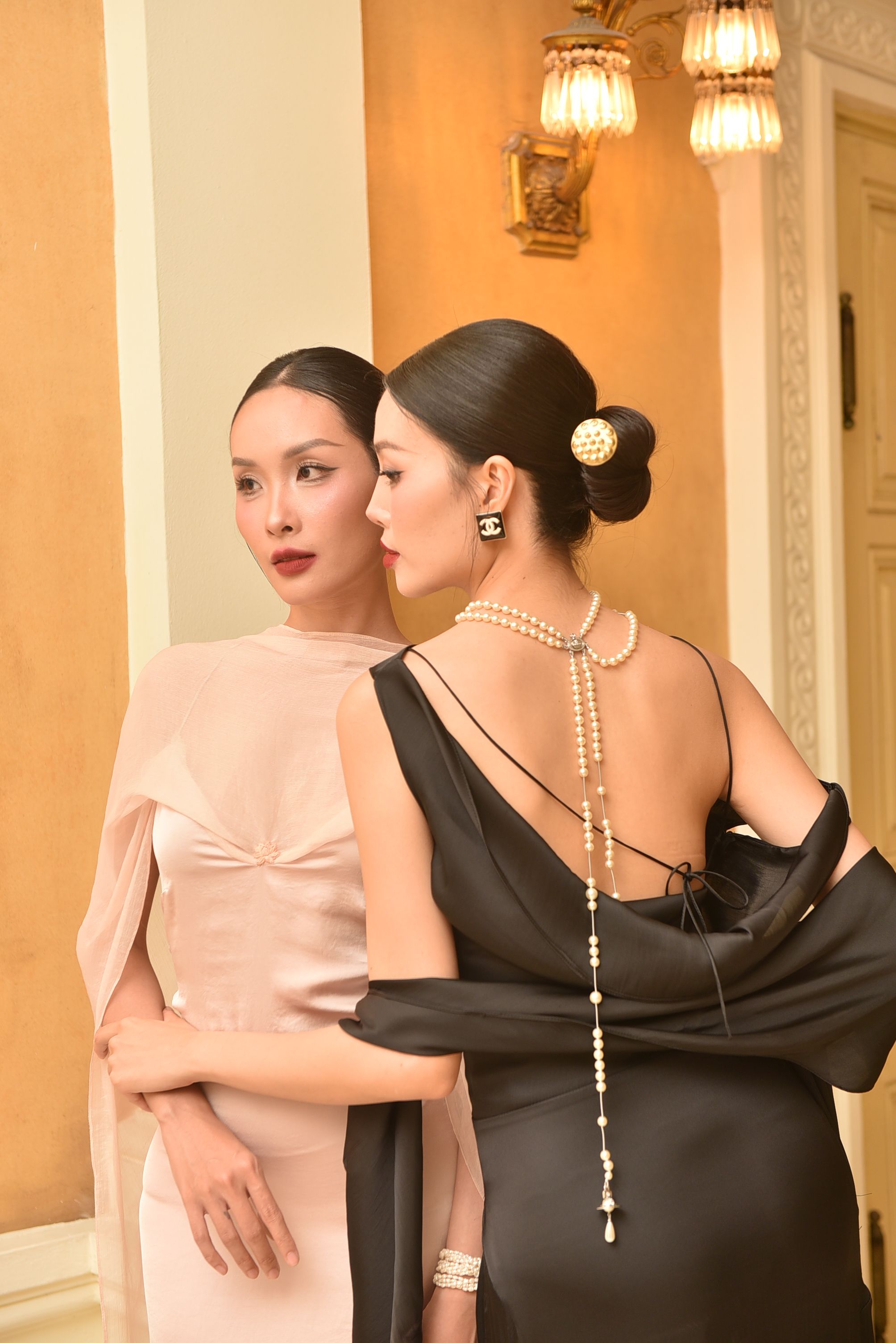 Stylish portrayal of two women in elegant attire indoors, featuring classic fashion and chic accessories.