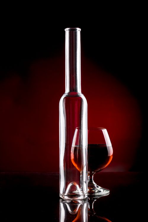 Free Stylish image of a wine bottle and glass against a bold red and black backdrop, perfect for luxury themes. Stock Photo