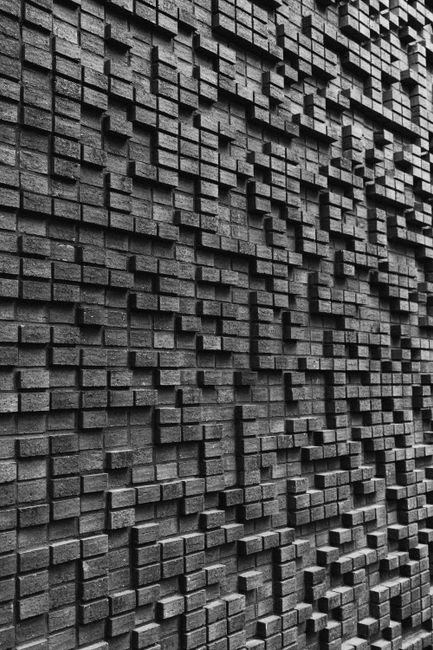 Detailed abstract brick wall with geometric patterns creating a 3D texture.