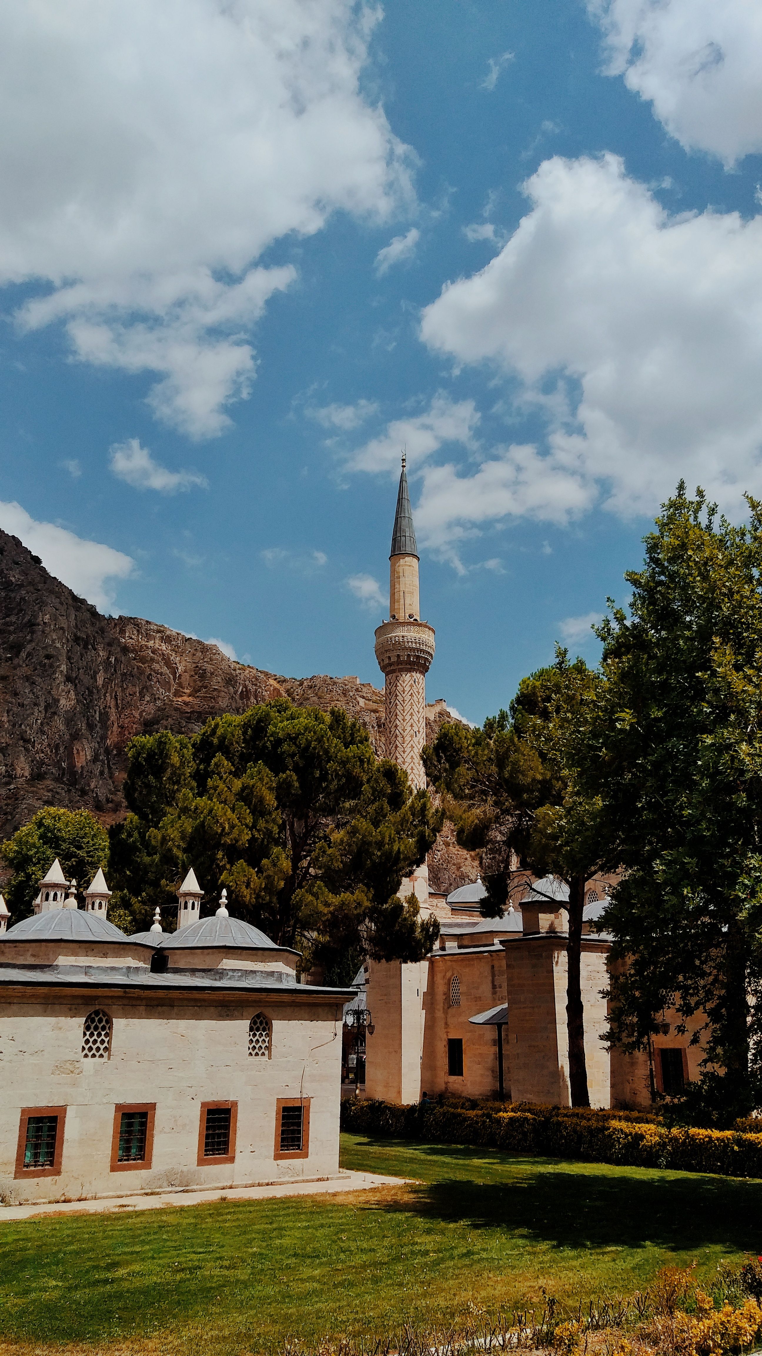 Scenic view of a mosque with a towering minaret against a backdrop of mountains in Amasya, Türkiye.