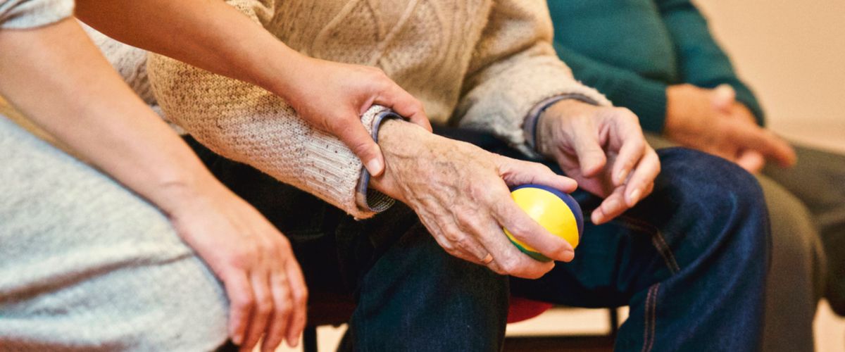 Cuidadora segurando a mão de uma pessoa idosa — cuidados paliativos