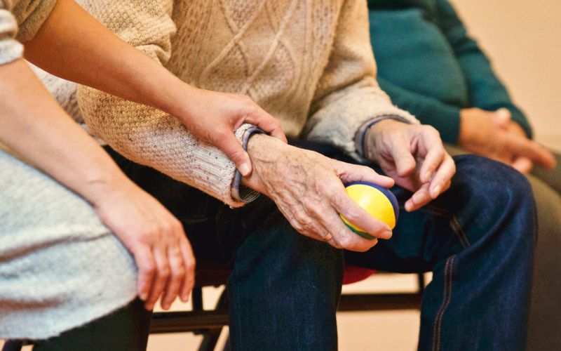 Younger hands gently supporting an elderly hand