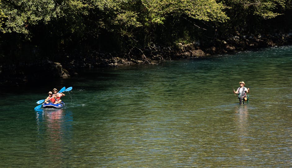 A serene view of people kayaking and fishing on a picturesque river in France.