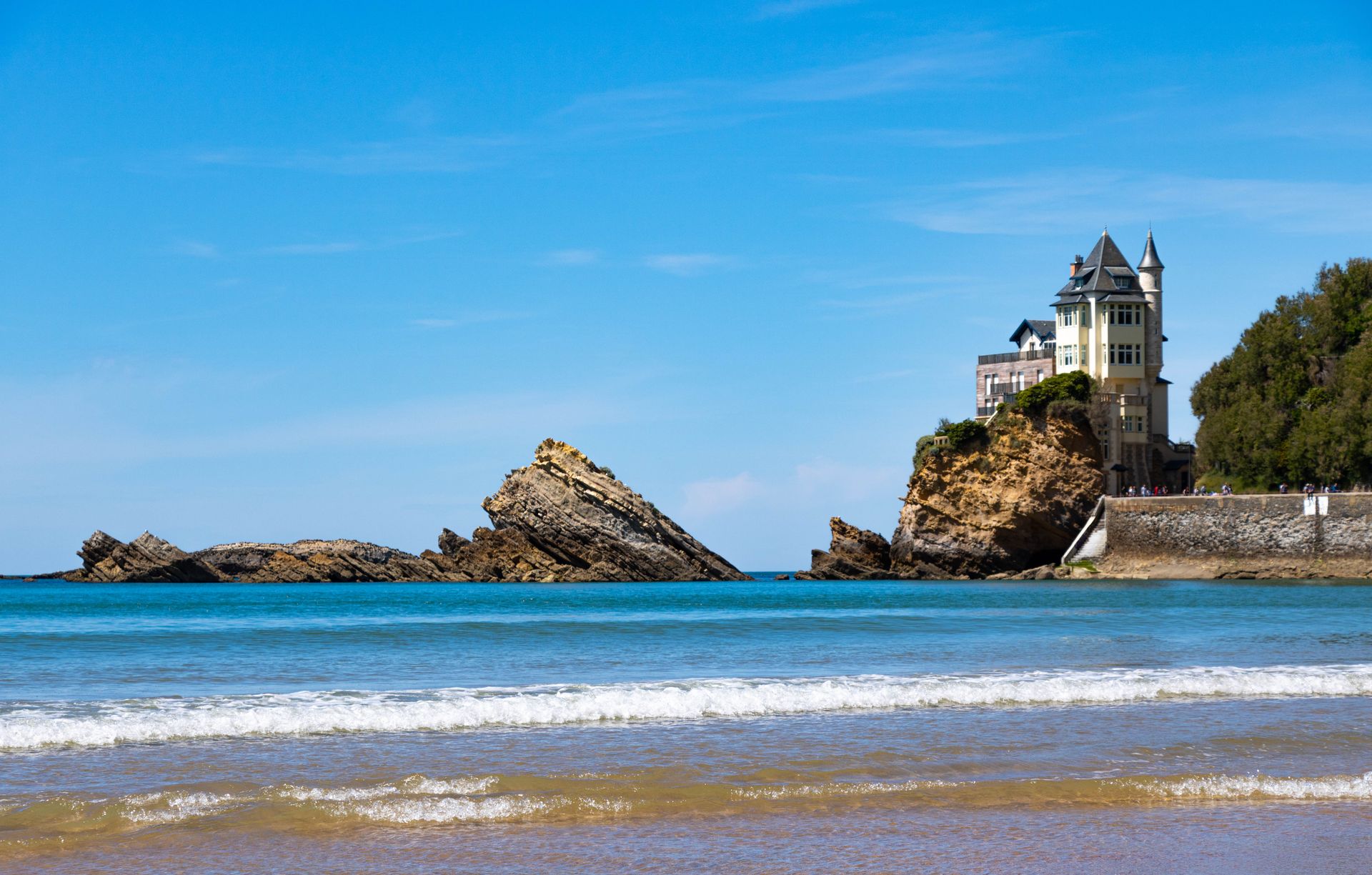Stunning coastal architecture in Biarritz, France with a rocky seascape under a clear blue sky.