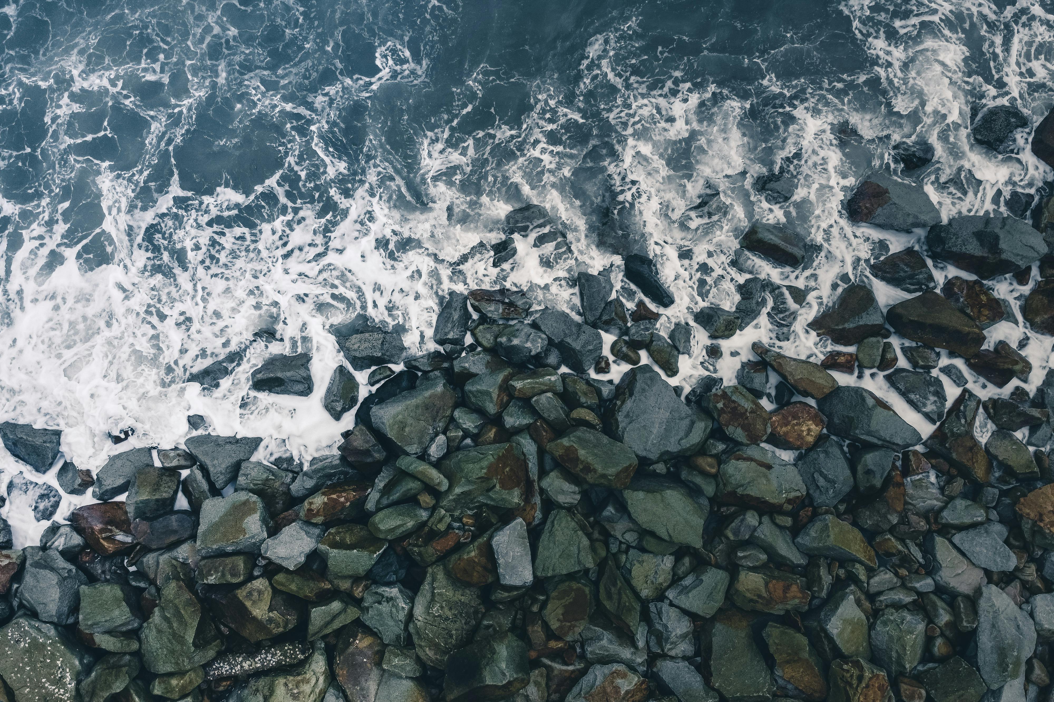 航拍镜头捕捉到海浪拍打崎岖海岸岩石的景象，展现了海洋的自然美景