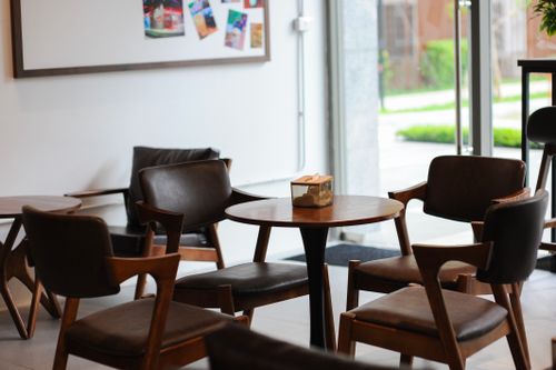 Free Warm and inviting coffee shop interior in Hà Nội, Việt Nam with modern wooden furniture and large windows. Stock Photo
