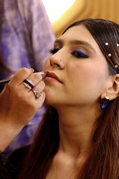 A woman getting professional makeup applied, focusing on elegant eye and lip detailing.