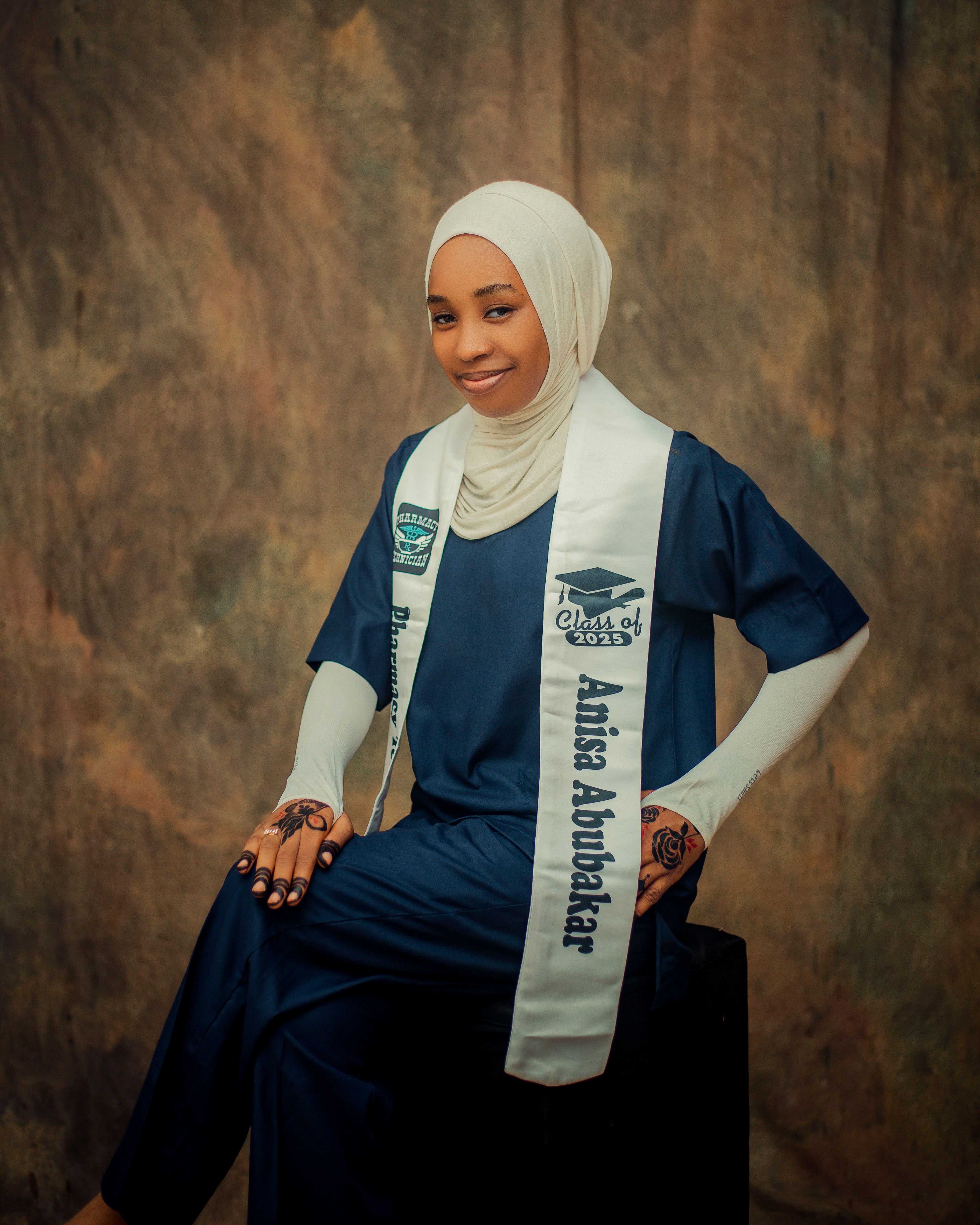 Young woman posing in cap and gown celebrating graduation in a studio setting.