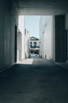 Peaceful view of a narrow urban alley leading to a house and parked car, captured in daylight.