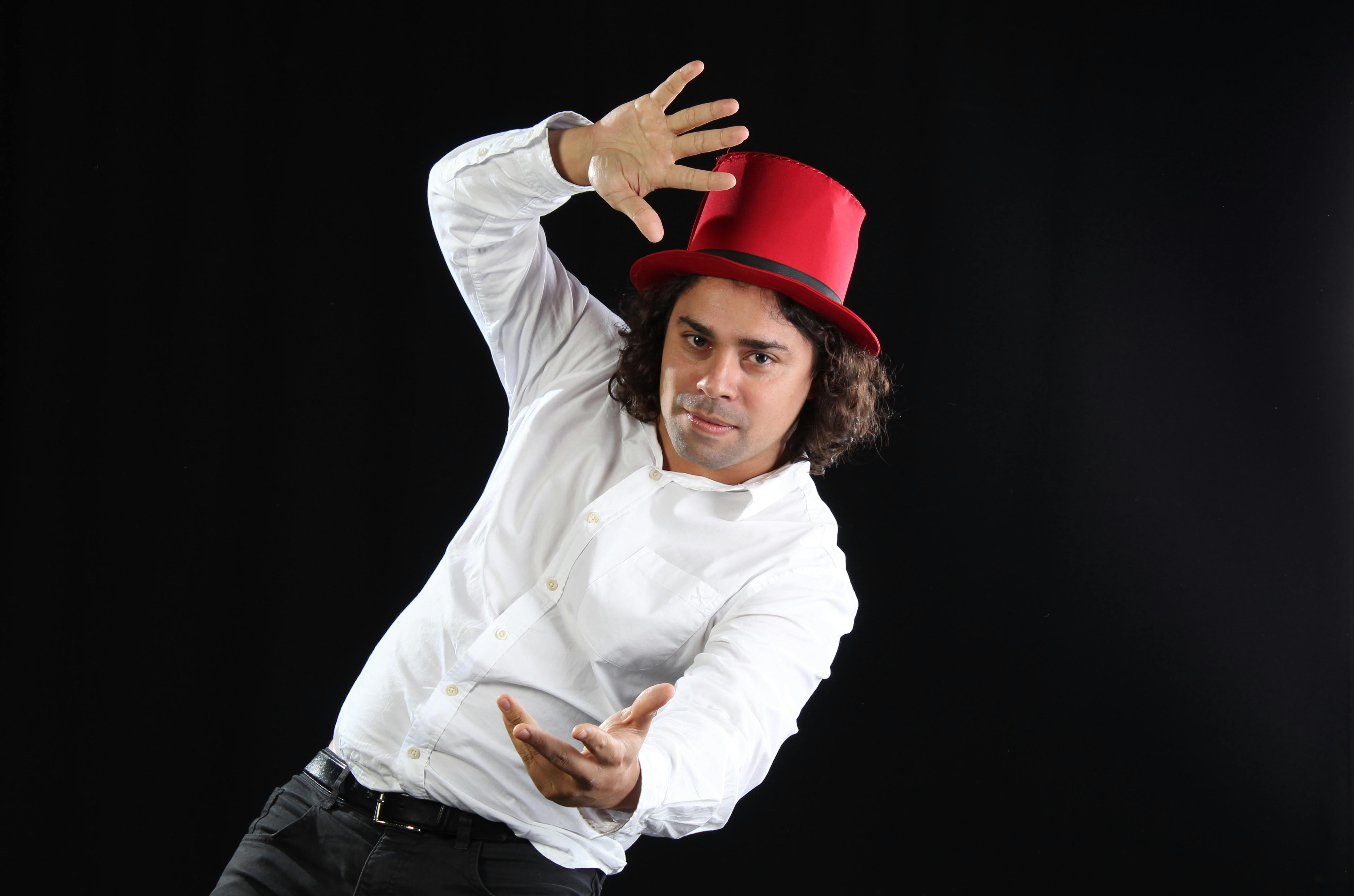 Free Engaging portrait of a man in a red top hat posing against a black background, capturing a dynamic movement. Stock Photo
