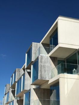 Contemporary architectural design with clean lines and glass balconies under a bright blue sky.