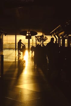 Travelers silhouetted against a captivating golden sunset at an airport terminal, conveying wanderlust.