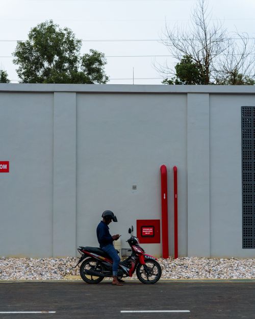 Free A motorcyclist checks his phone while parked against a minimalist urban wall. Stock Photo