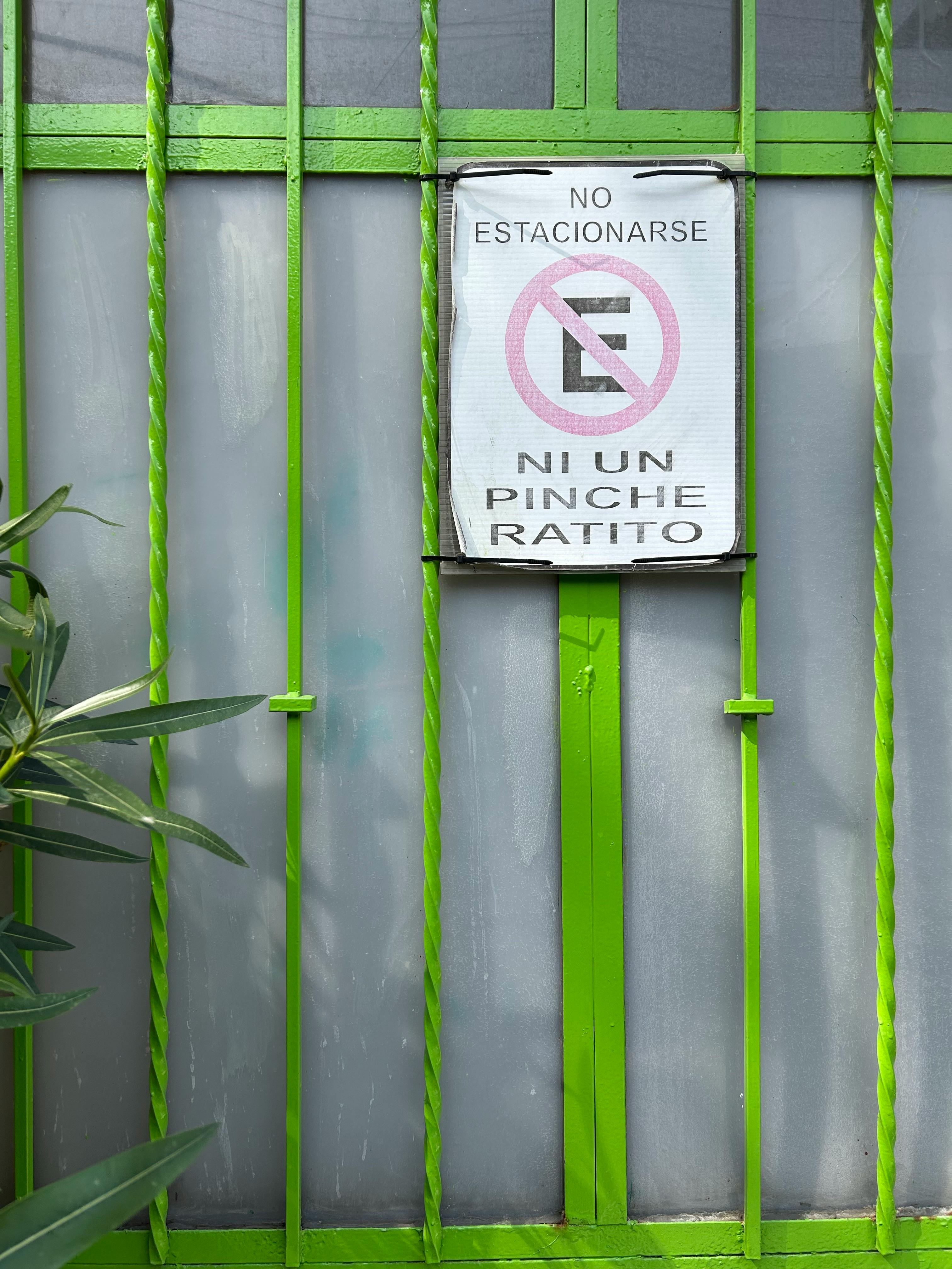 бесплатная Крупный план ярко-зеленых металлических ворот с юмористическим знаком, запрещающим парковку, в Мехико. Стоковое фото