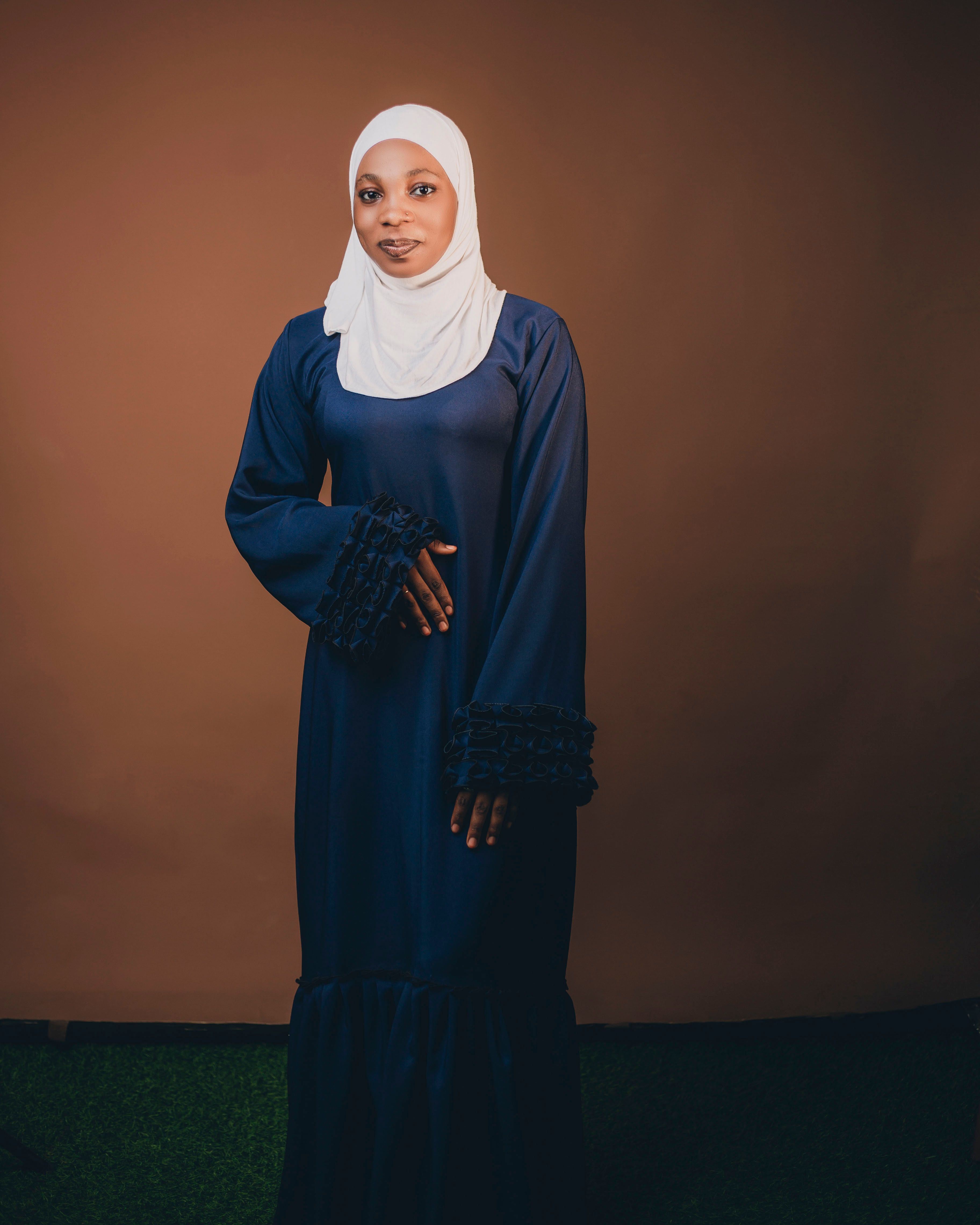 Elegant Woman in Hijab Standing Against Brown Backdrop · Free Stock Photo