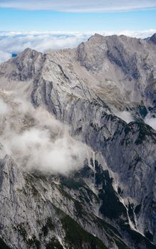 A breathtaking aerial view of the rugged mountain range in Tirol, Austria, shrouded in clouds.
