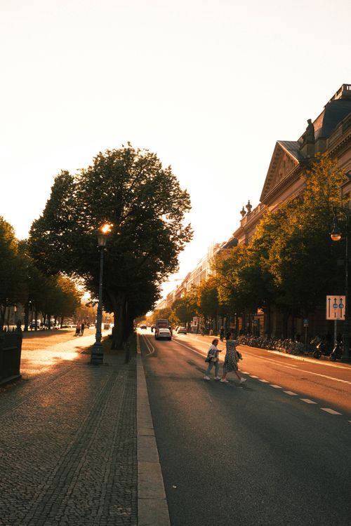 Free A vibrant sunset casts golden light on a Berlin street, capturing urban life and historic architecture. Stock Photo