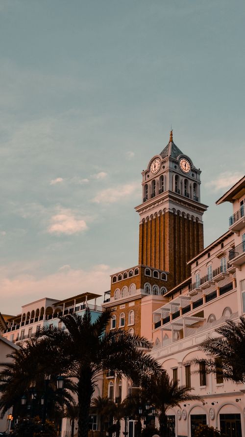 Free Stunning view of a historic clock tower with palm trees and evening sky. Stock Photo