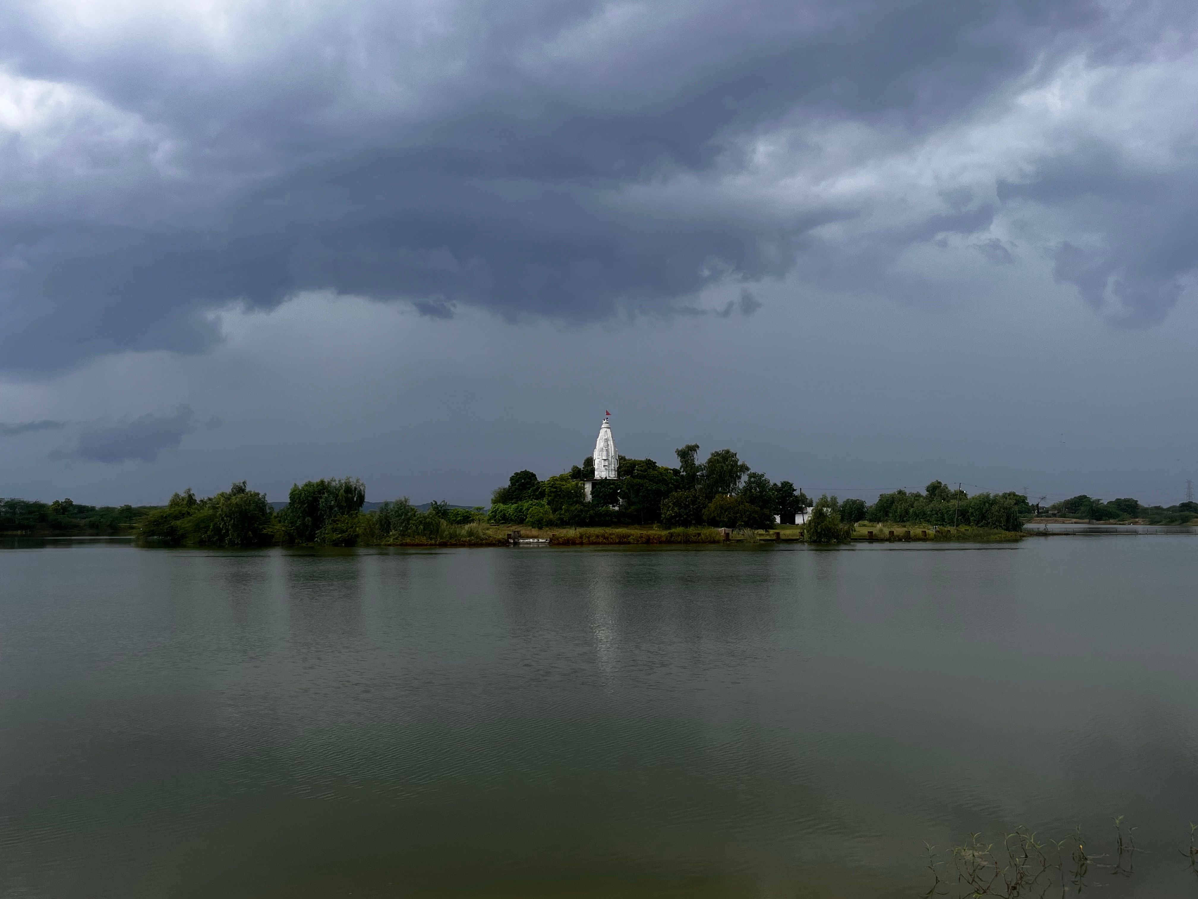 Majestic temple surrounded by lush greenery on an island with dramatic storm clouds.