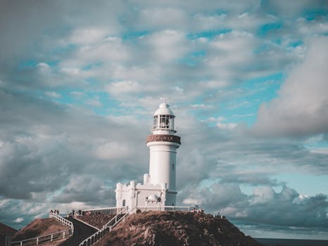 Majestic view of Cape Byron Lighthouse surrounded by dramatic clouds and a vibrant sky.