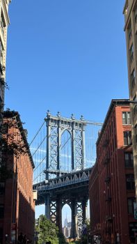 Iconic view of the Manhattan Bridge framed by red brick buildings in Dumbo, Brooklyn.