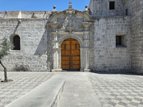 Free Beautiful ornate stone facade featuring a wooden door in bright daylight. Stock Photo