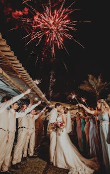 在烟花下，新娘和新郎接吻，婚礼宾客手持烟花