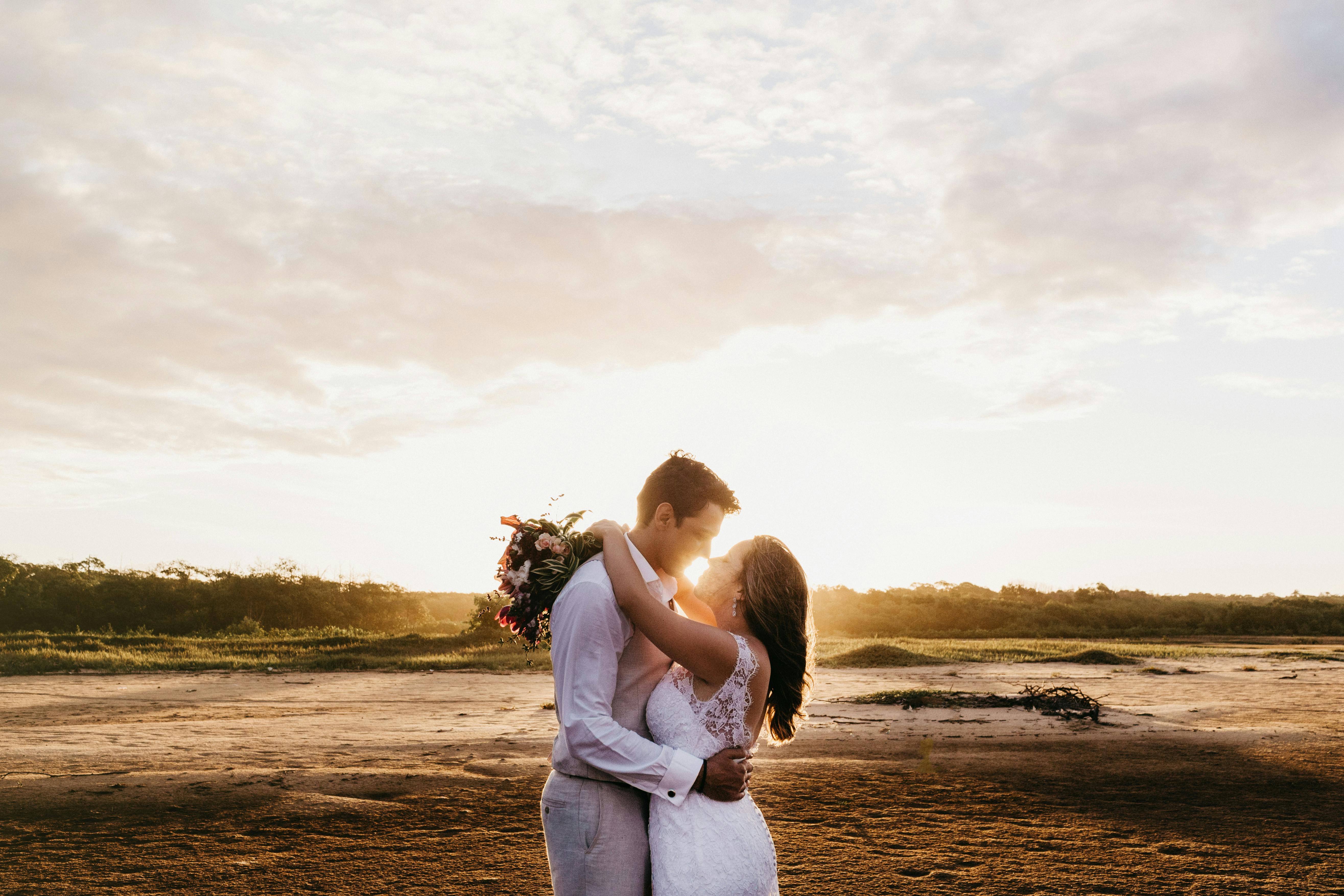 日落时分，新娘和新郎在海滩上相拥，象征着爱与团结