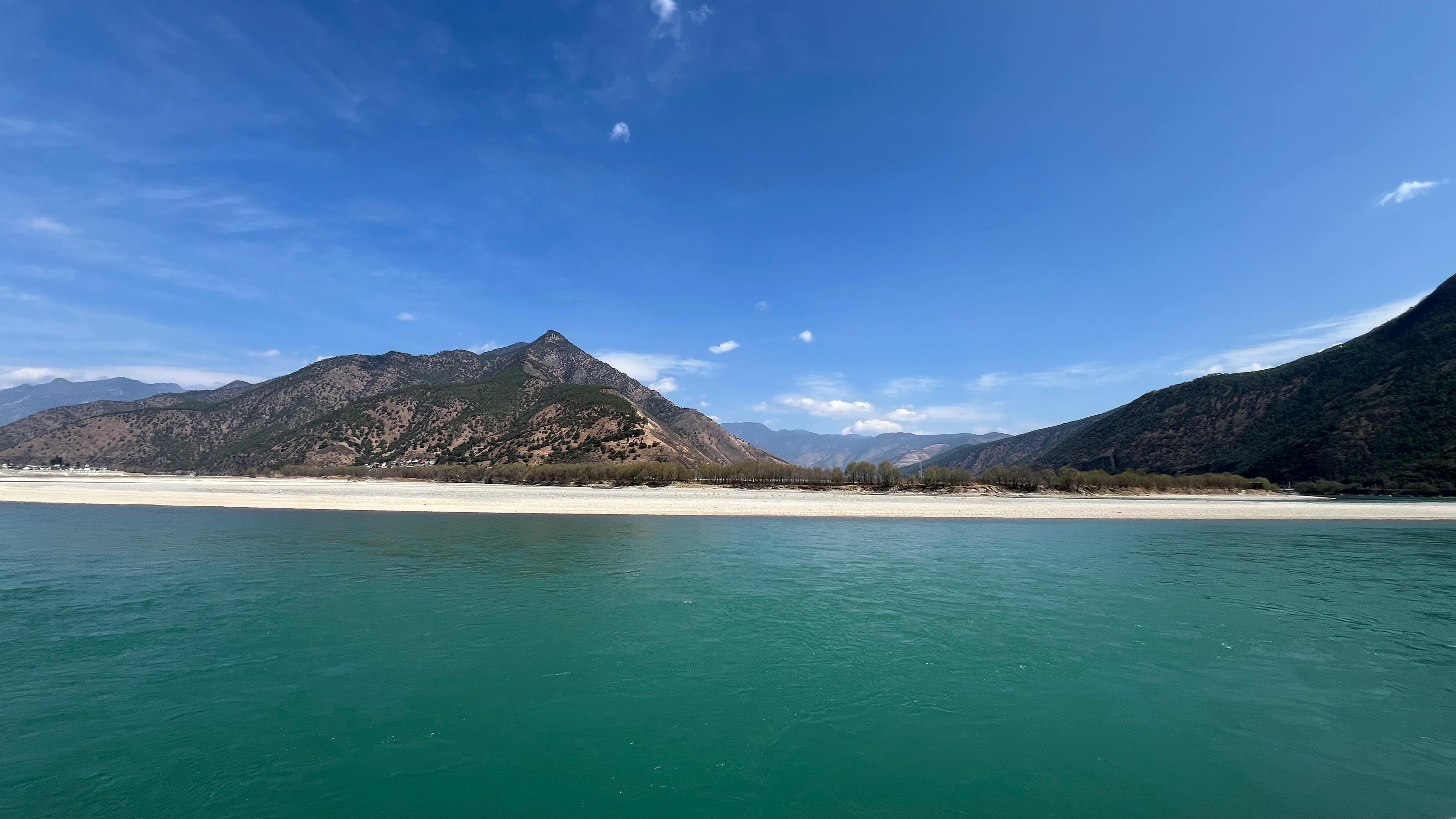 Serene view of mountains and blue sky over a calm lake, capturing natural beauty.