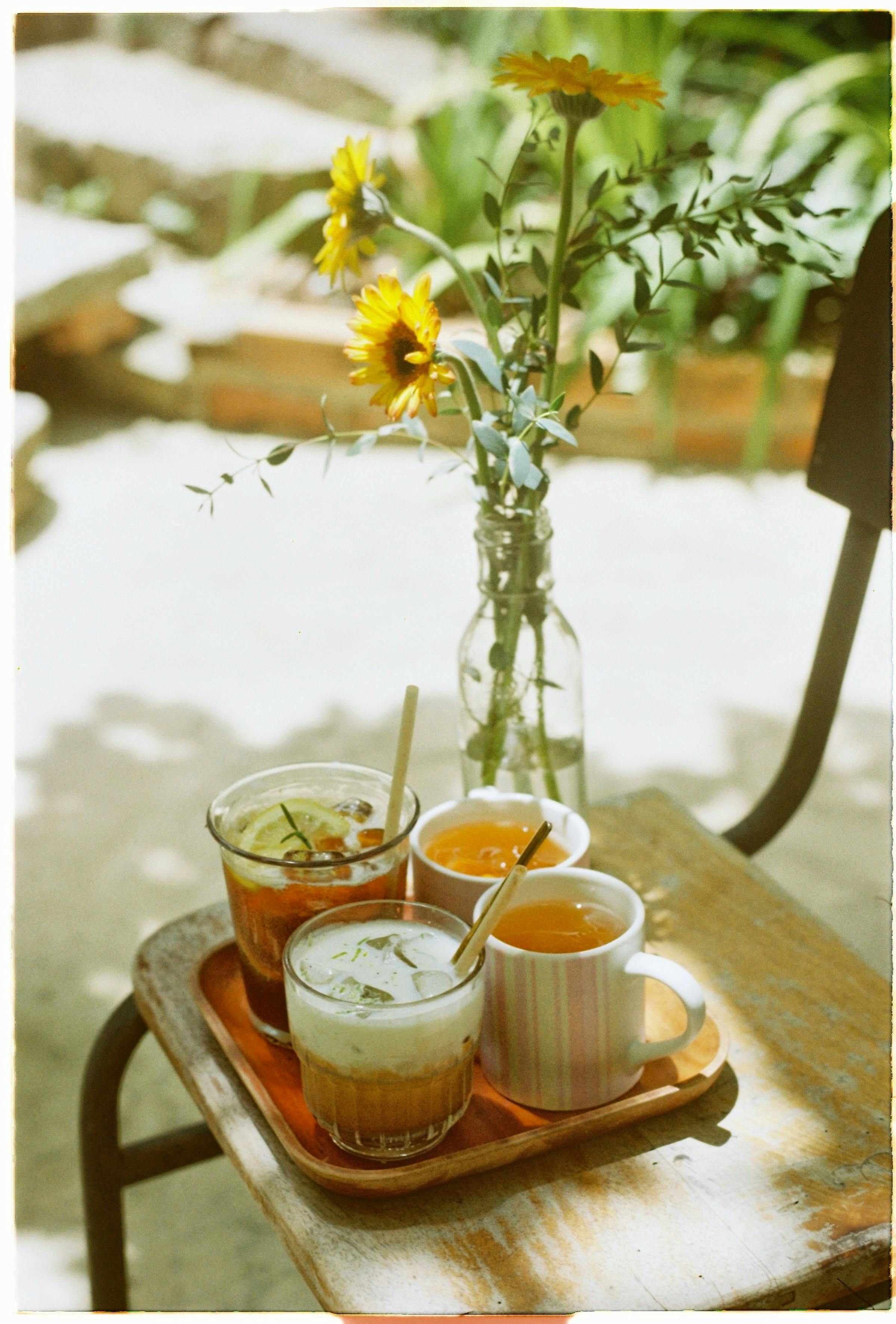 A cozy outdoor tea setting featuring various drinks and vibrant sunflowers on a sunny day.
