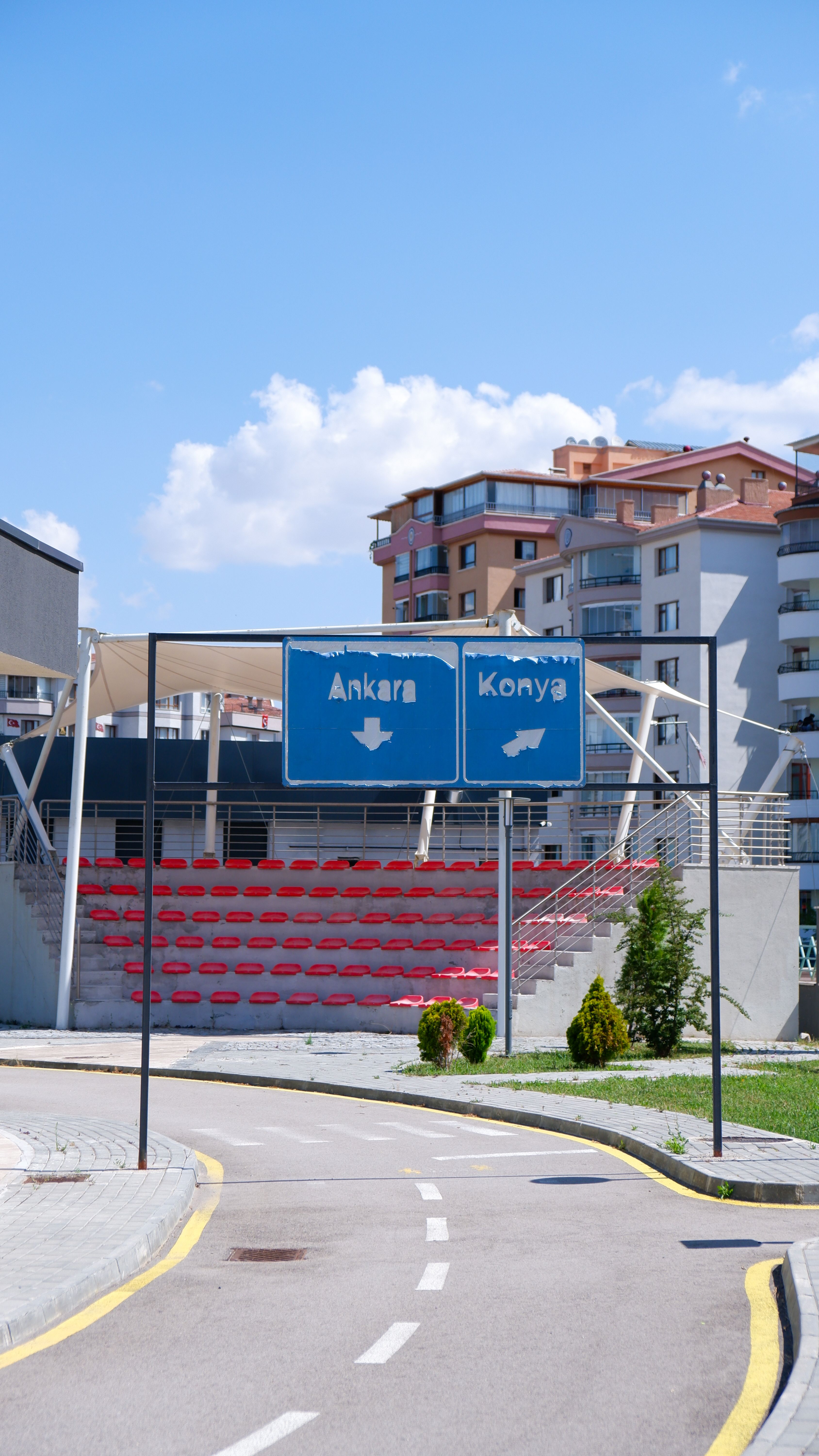 Street scene in Ankara showing directional signs to Konya amid modern buildings and clear skies.