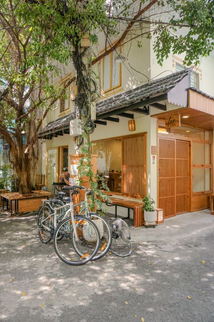 A scenic café exterior in Hồ Chí Minh City with bicycles parked under lush greenery.