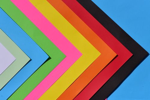 Free Vibrant layers of colorful paper sheets arranged in a geometric pattern with a blue background. Stock Photo