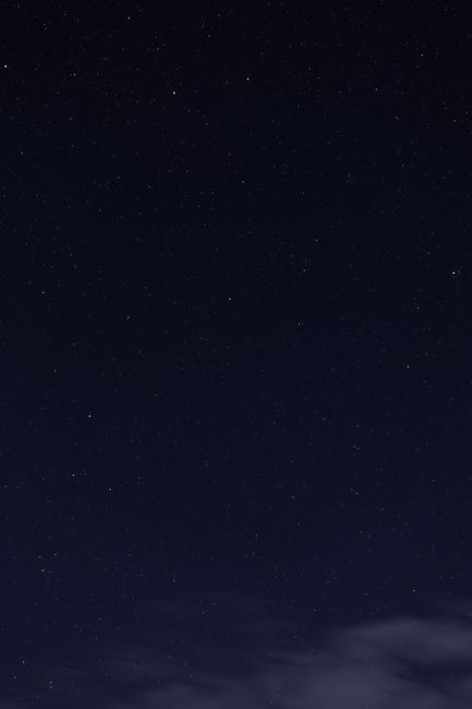 A serene night sky full of twinkling stars with a hint of clouds visible.