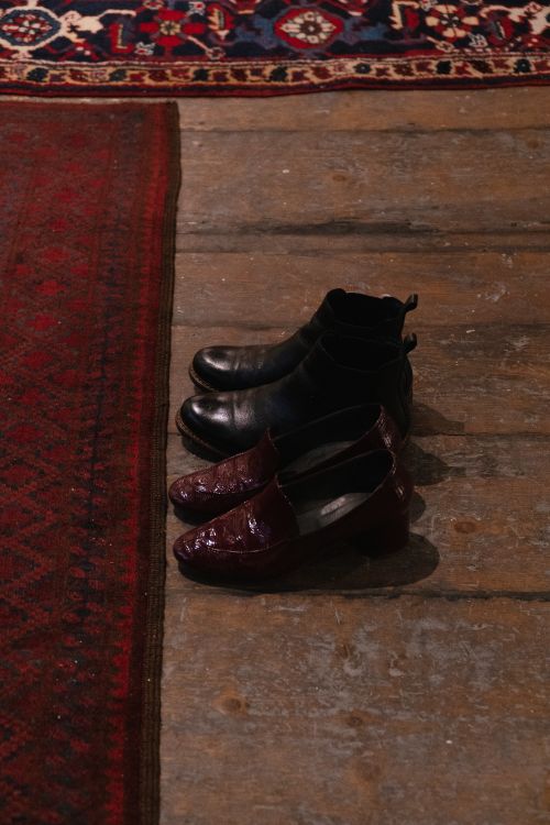 Free Stylish shoes placed on an elegant wooden floor beside a vintage rug. Stock Photo