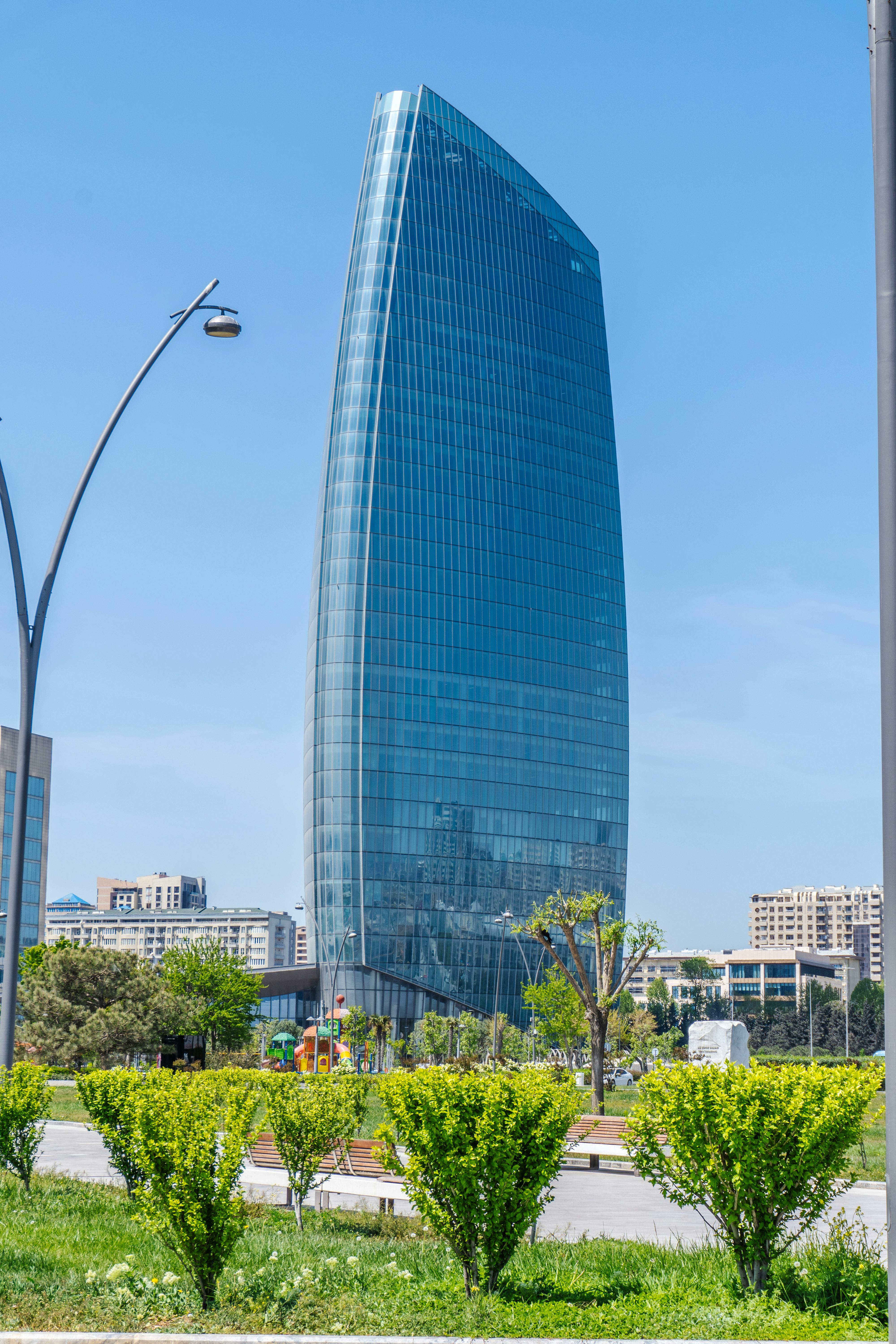Tall modern skyscraper with glass facade in Baku, Azerbaijan under clear blue sky.