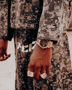 Close-up of a camo outfit with elegant rings and watch.
