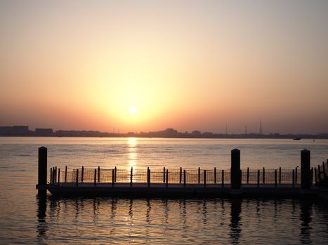 Beautiful sunset view over a calm waterfront pier in Doha, Qatar, capturing tranquility.