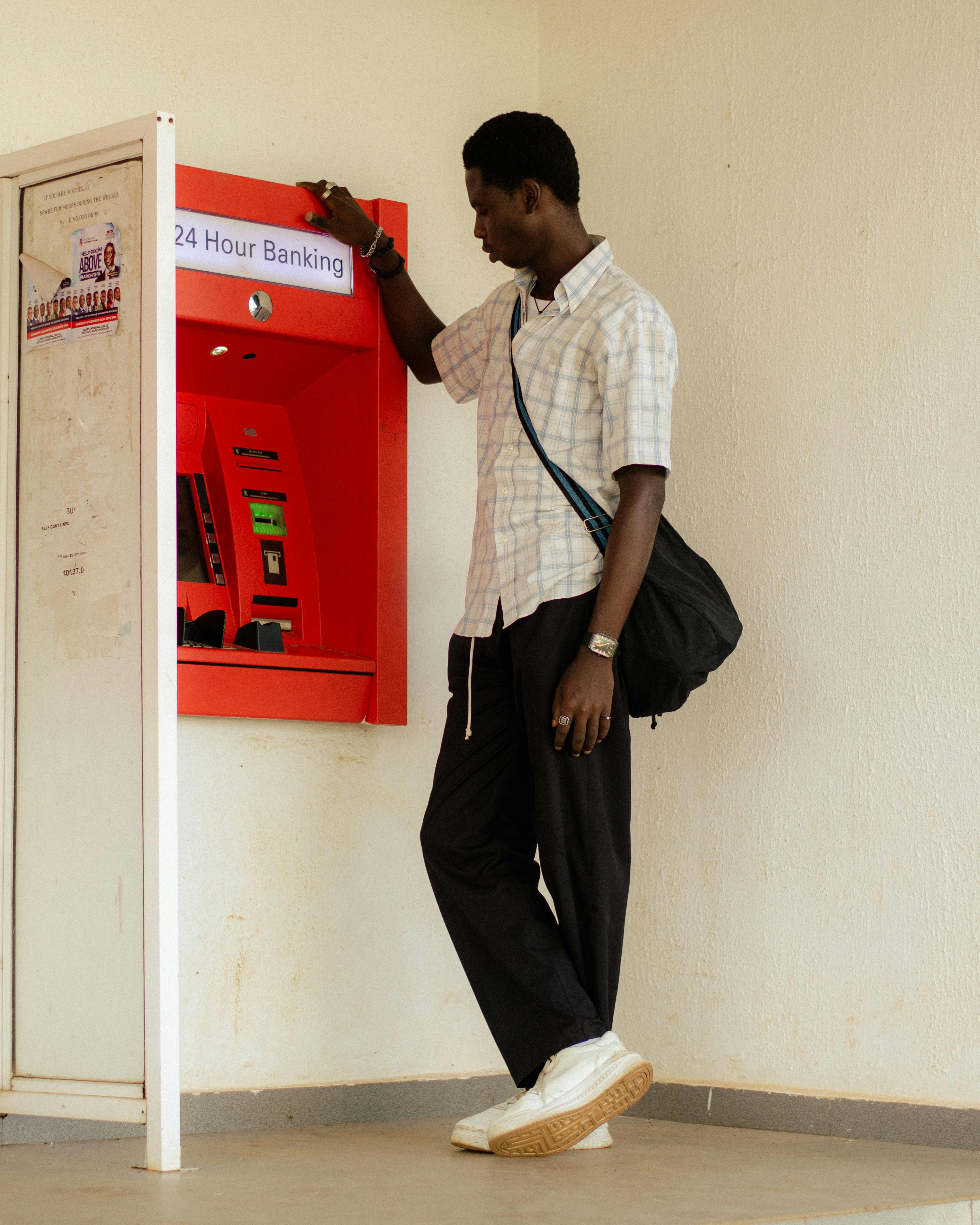 A man interacts with a 24-hour ATM machine, highlighting modern banking convenience.