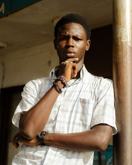 Free Young man in a pensive pose in outdoor setting, sunlit. Stock Photo