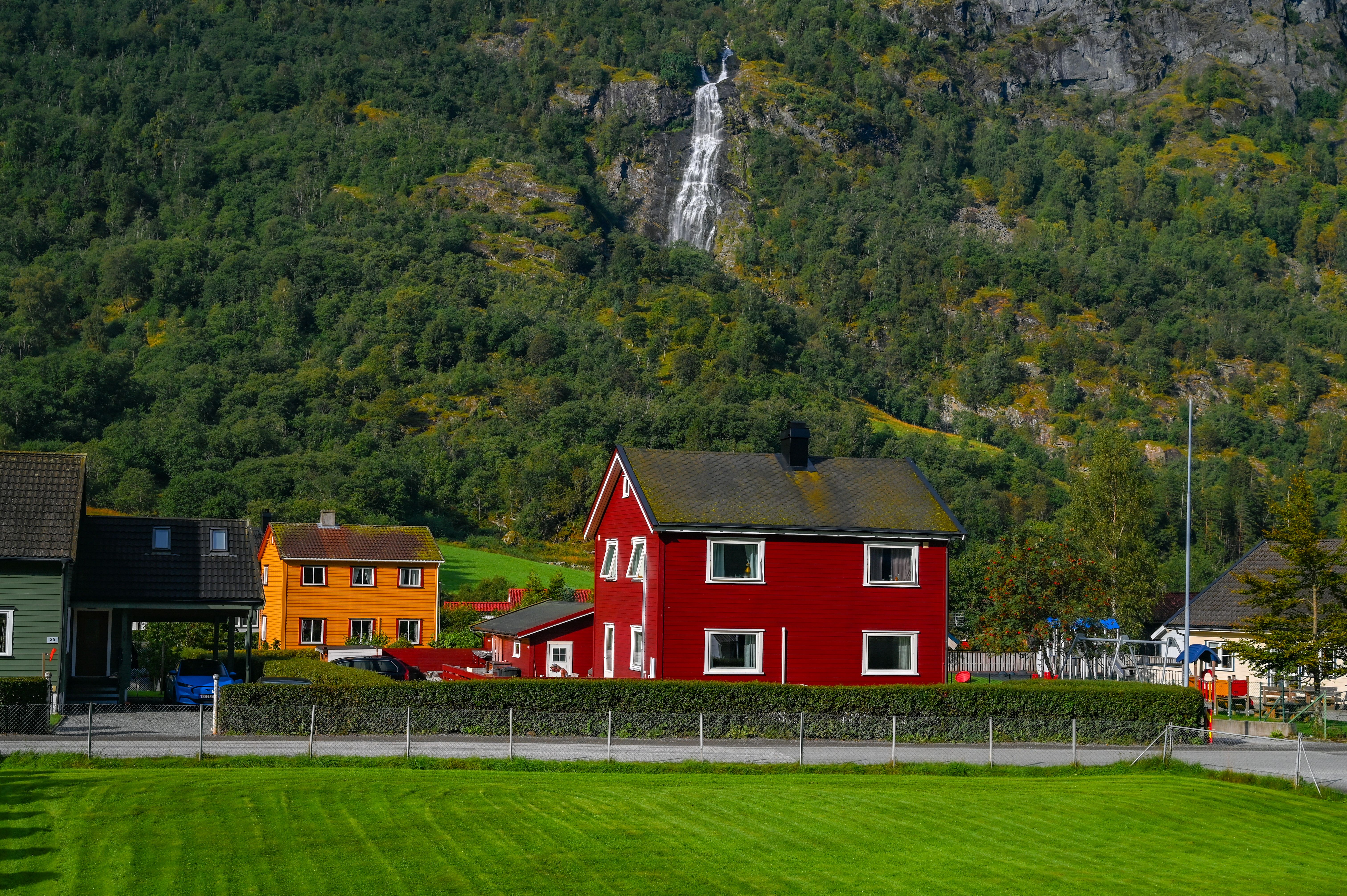 Charming Nordic village with colorful houses, lush greenery, and a picturesque waterfall in the background.