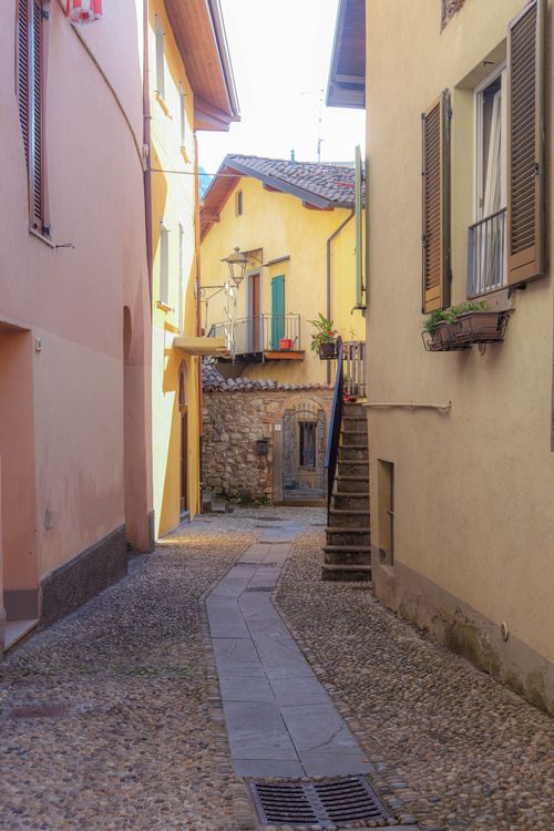 Free A quaint narrow alley in an Italian village, showcasing rustic architecture and cobblestone path. Stock Photo