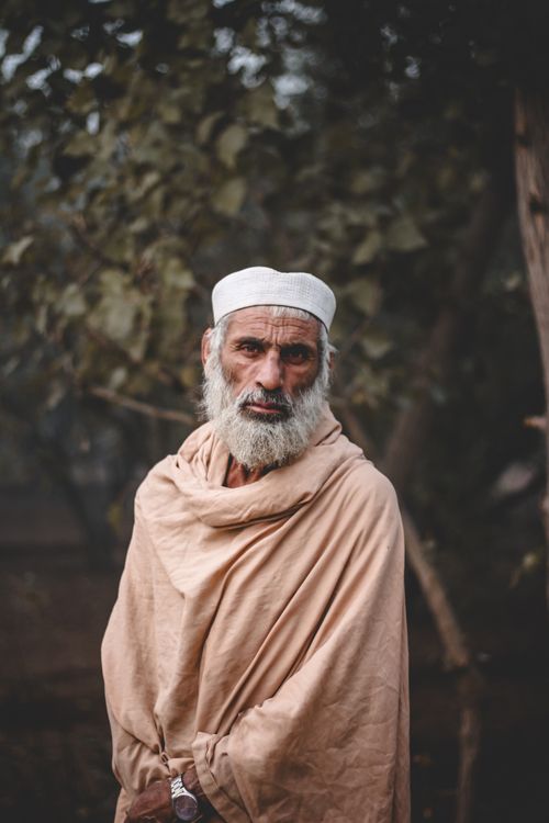 Free A dignified elderly man with a white beard in traditional clothing, posing outdoors. Stock Photo