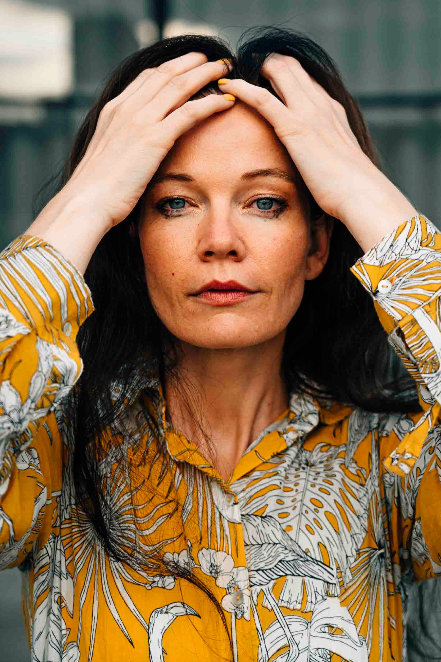 Close-up portrait of a woman in Berlin wearing a vibrant yellow floral shirt.
